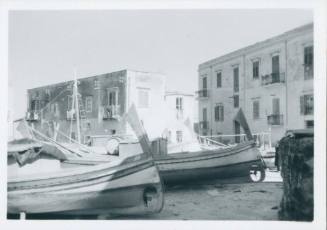 Two grounded fishing boats in foreground with Porticello apartments in background