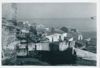 View of coastal village with sea in the background and the wall of a building to the left