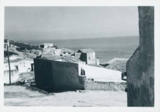 View of coastal village with sea in the background and the wall of a building to the right