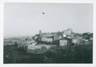 Skyline of an Italian town from a distance. Two bell towers stick out from the mass of buildings