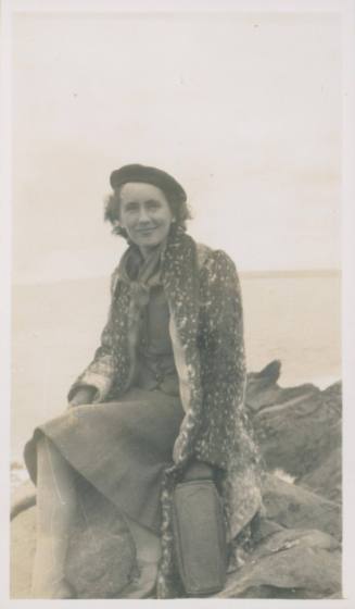 Wilhelmina Barns-Graham sitting on rock in fur coat and beret.
