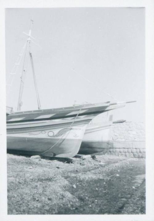 Two grounded fishing boats, with a sea wall in the background