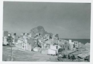 View of St Elia looking out towards the sea, with village in the foreground and rocky island in background