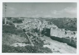 Sicilian town from a straight road that leads into the town centre. Hilly scrubland to the left and right