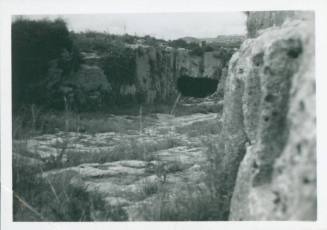 Rocky valley with the mouth of a cave in the distance