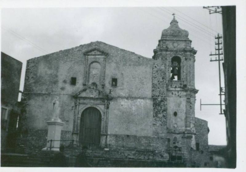 A church with a marble statue to the left of its entrance, and a belltower to its righthand side