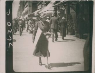 Wilhelmina Barns-Graham walking down Princes Street, Edinburgh, holding canvas. [Walking photo]