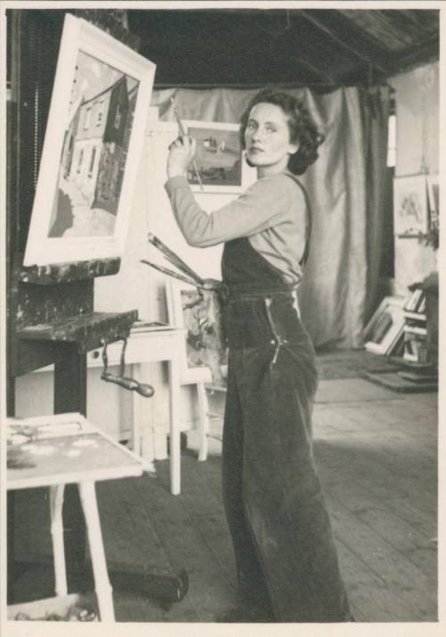 Wilhelmina Barns-Graham posing in front of "Grey Sheds No 2" on easel. No. 1 Porthmeor Studios.